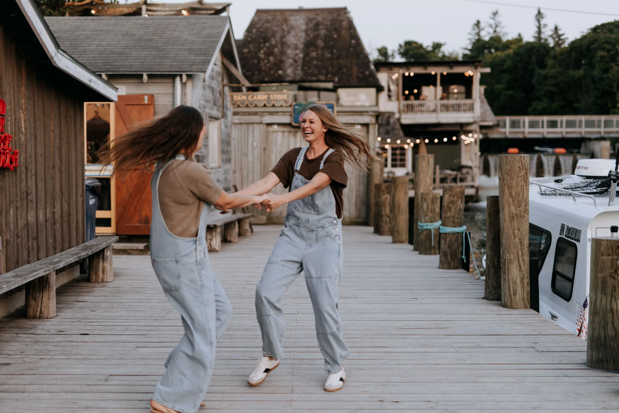 McKenzie and Kayla spinning together on the dock between the weathered shanties at Leland Marina