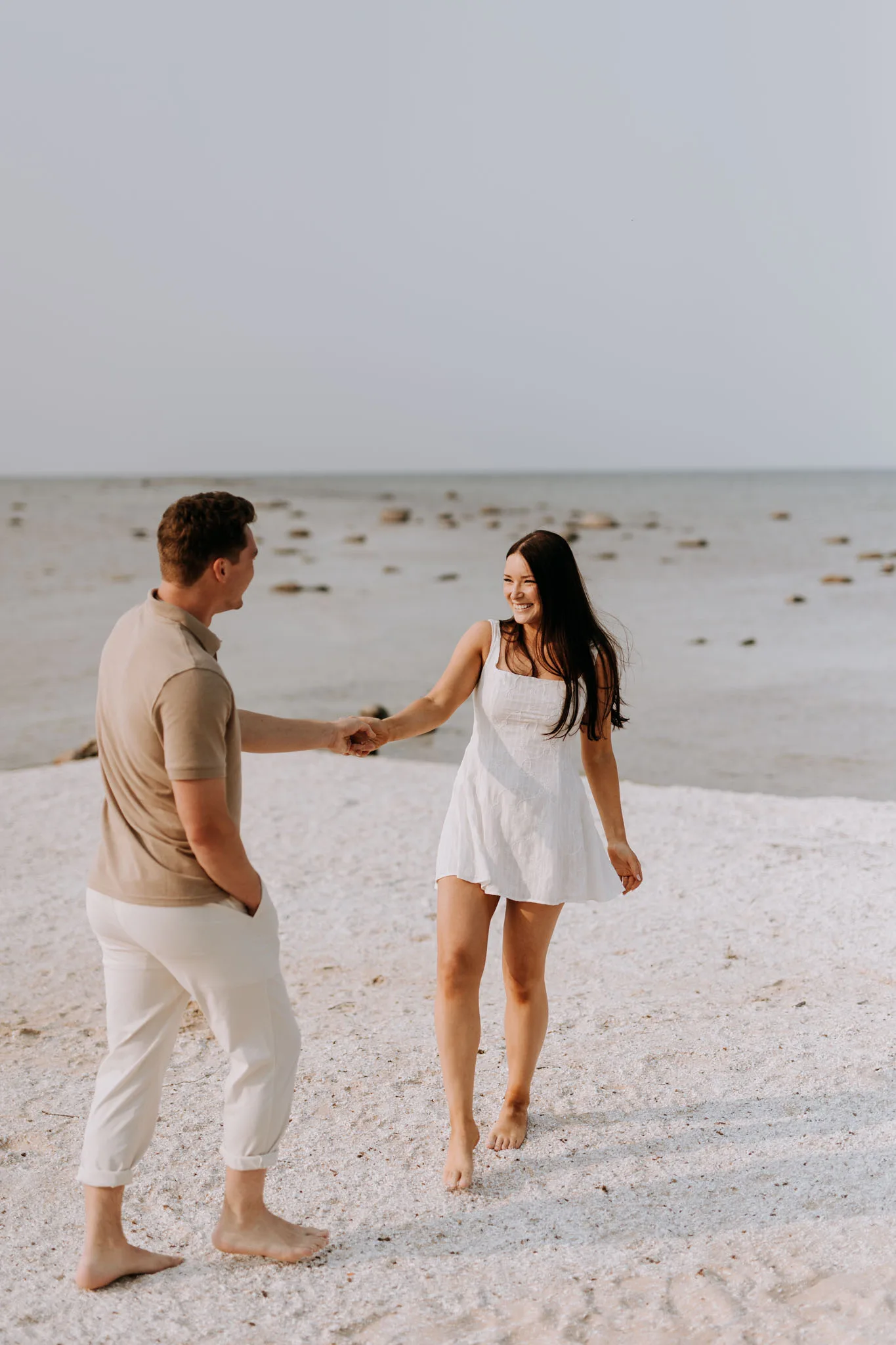 Newly engaged couple walking the Lake Michigan shoreline at sunset