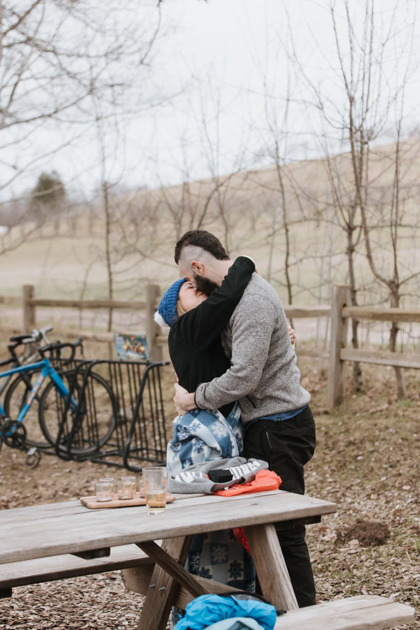 Tiffa and Karl sharing a tender embrace at a picnic table at Tandem Ciders