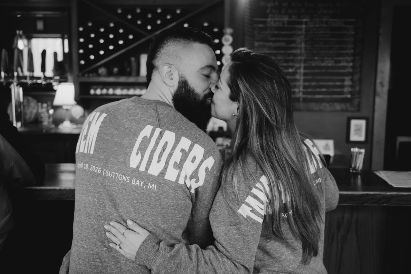 Tiffa and Karl kissing after the proposal at Tandem Ciders in Suttons Bay, Michigan