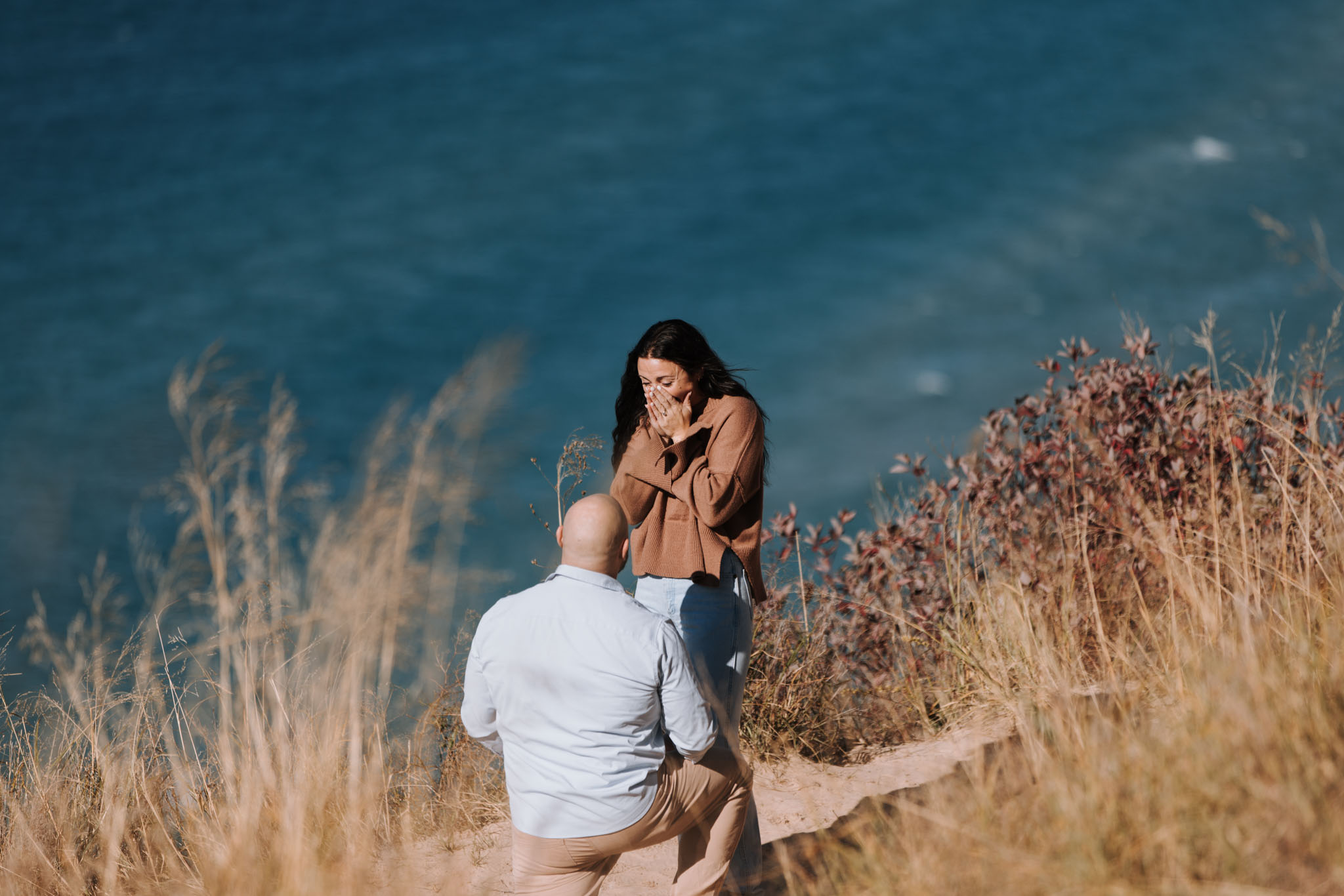 Couple at Pierce Stocking overlook, Lake Michigan behind them — surprise proposal photographed by Allen-Kent Photography