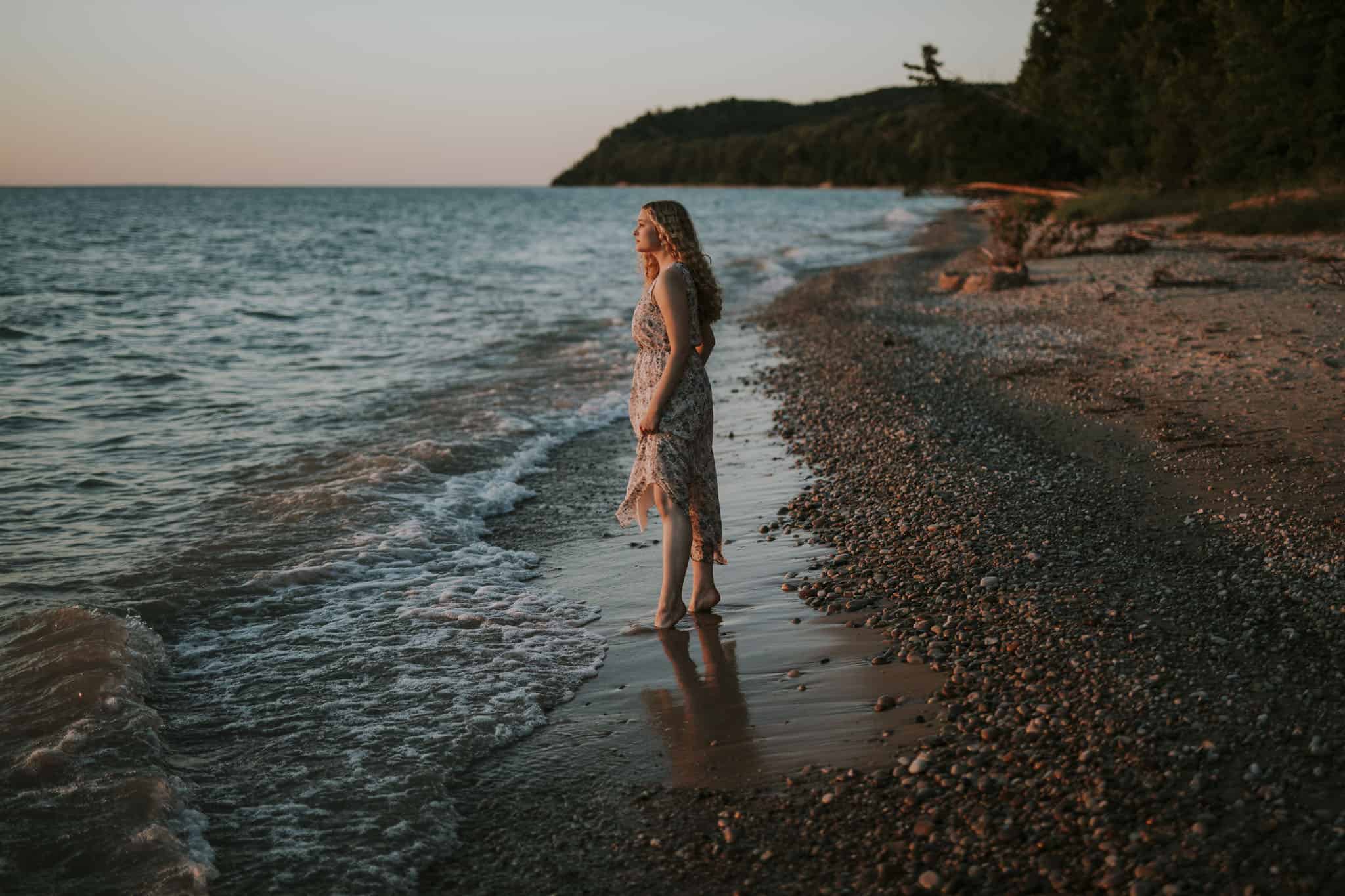 girl standing on a beach in northern michigan at sunset