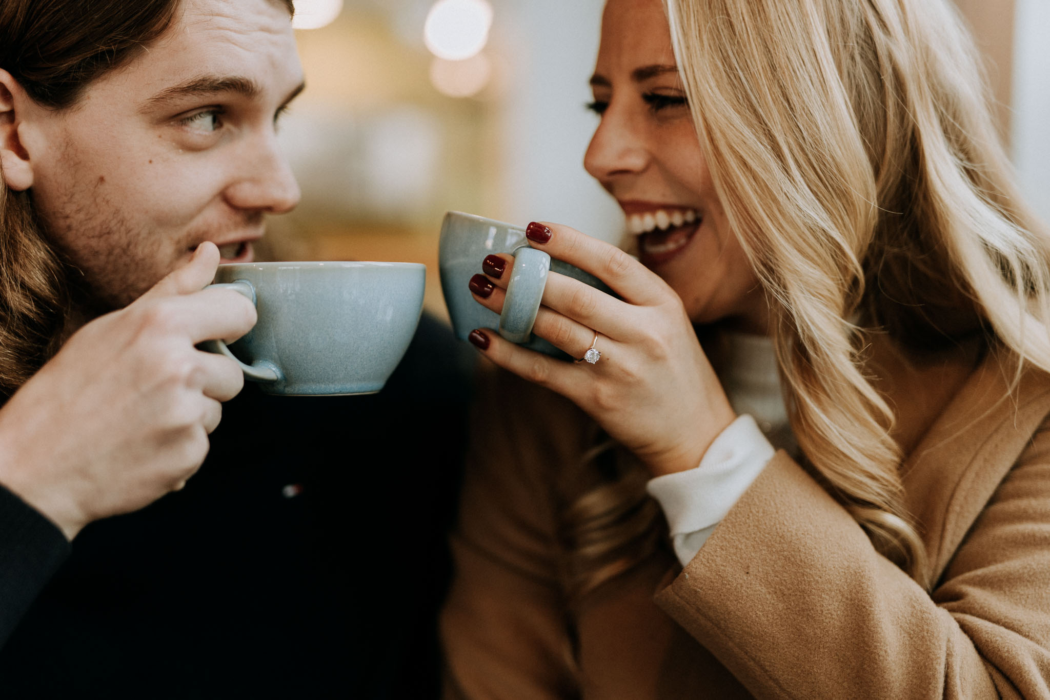 Couple laughing together indoors during the warm start of a winter engagement session in Traverse City