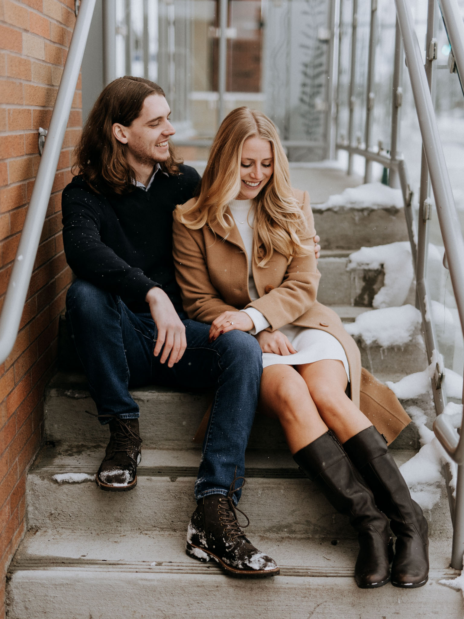 Couple sharing a warm drink indoors before heading outside for winter engagement photos in Traverse City