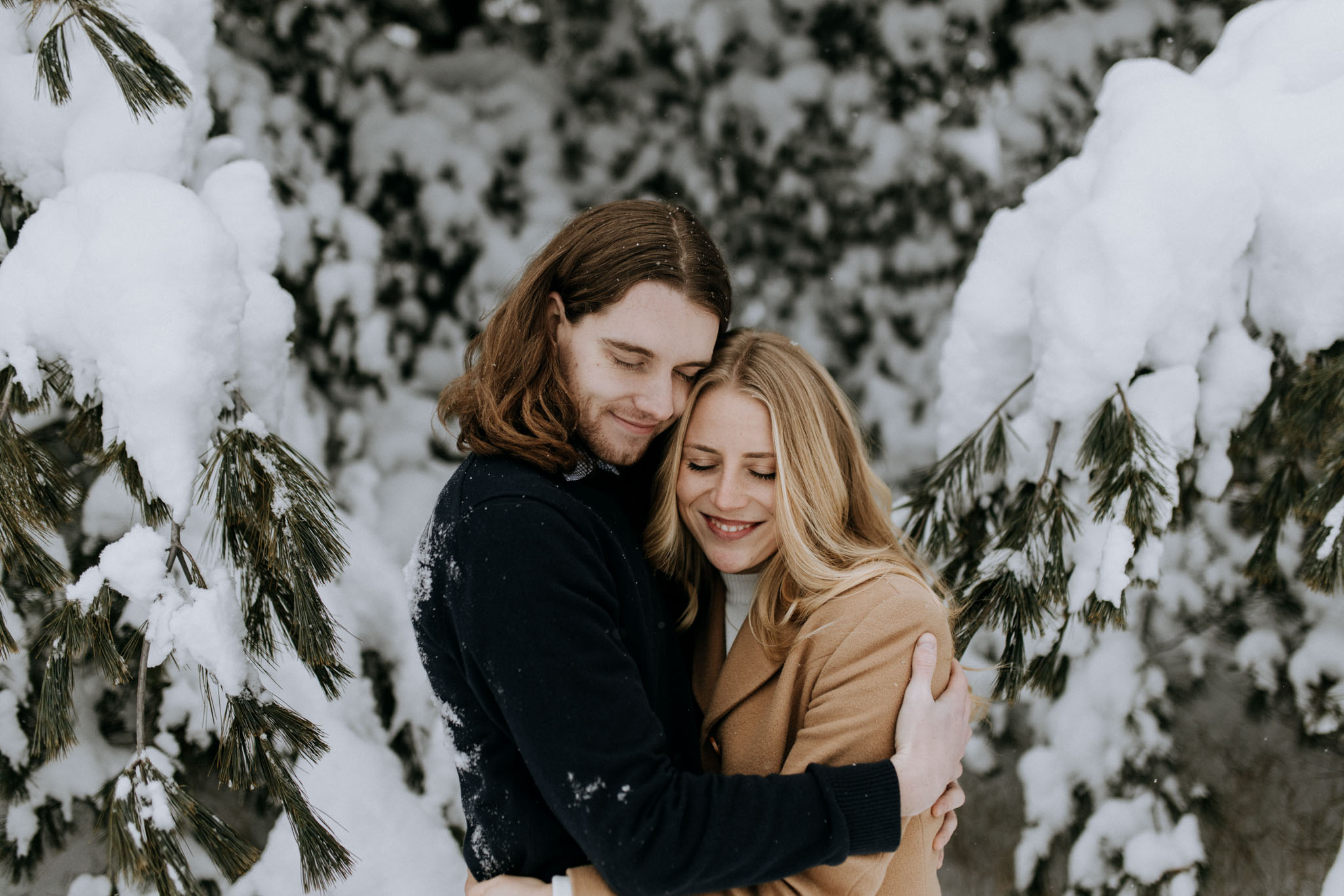 Couple holding each other on a snow-covered trail during outdoor portion of Northern Michigan winter engagement session