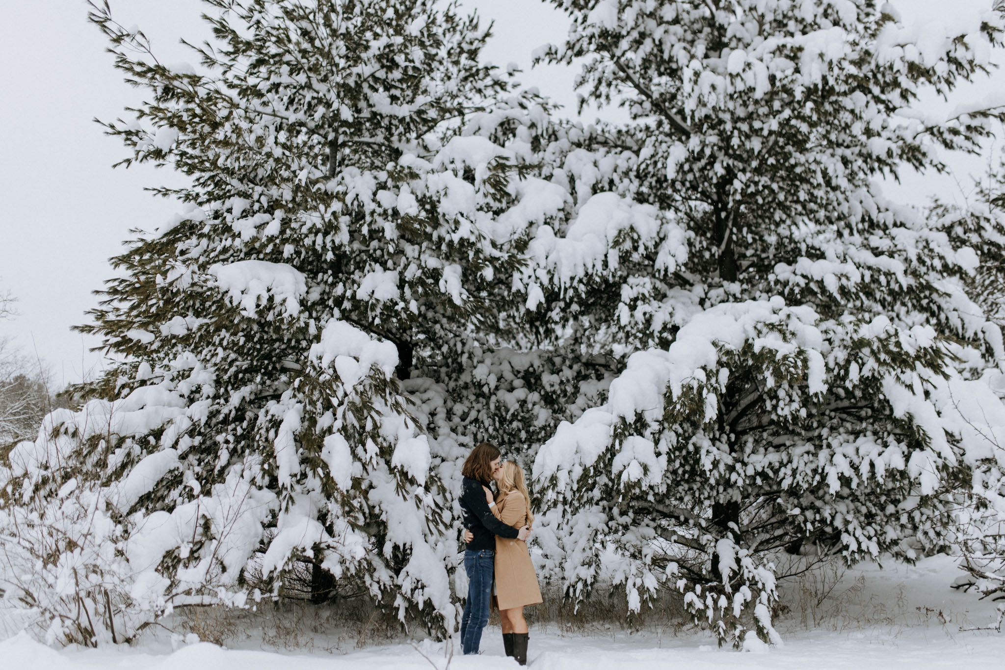 Couple walking downtown Traverse City streets in winter with snow on the ground during engagement session