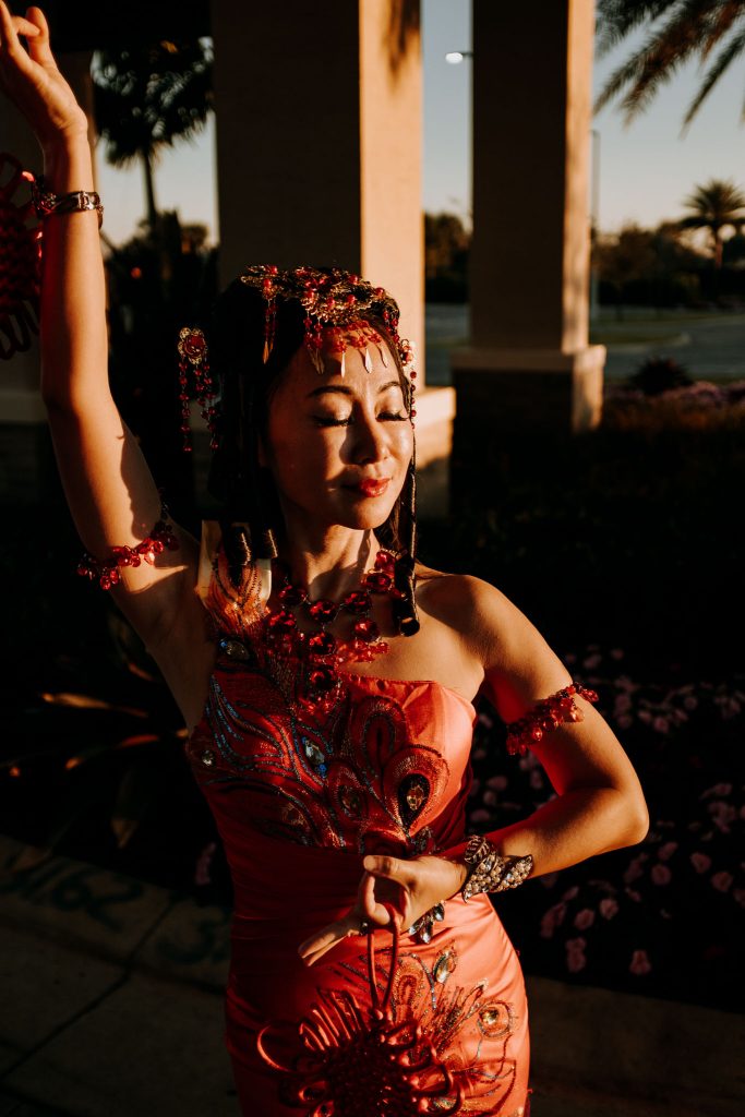 woman in traditional Chinese Dress posing in front of a palm tree