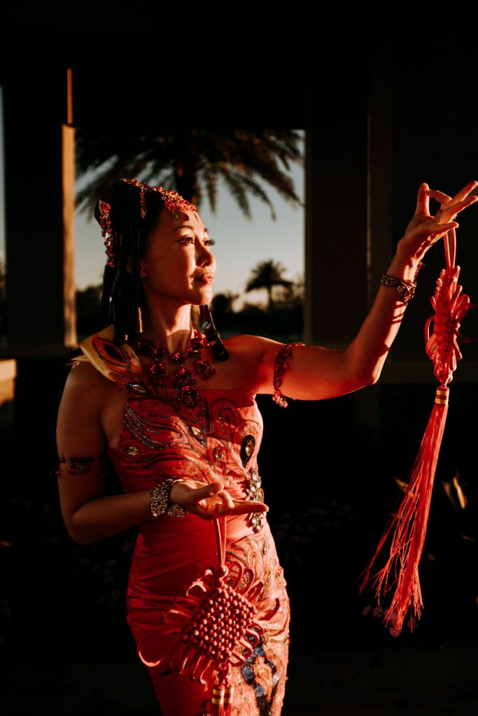 woman in traditional Chinese Dress posing in front of a palm tree