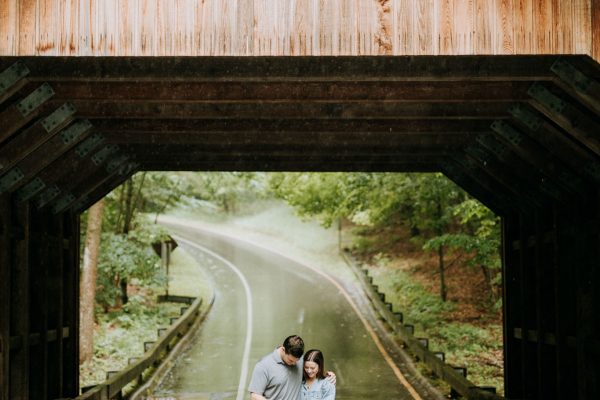 couple just after proposing to marry in the rain under the covered bridge on pierce stocking scenic drive