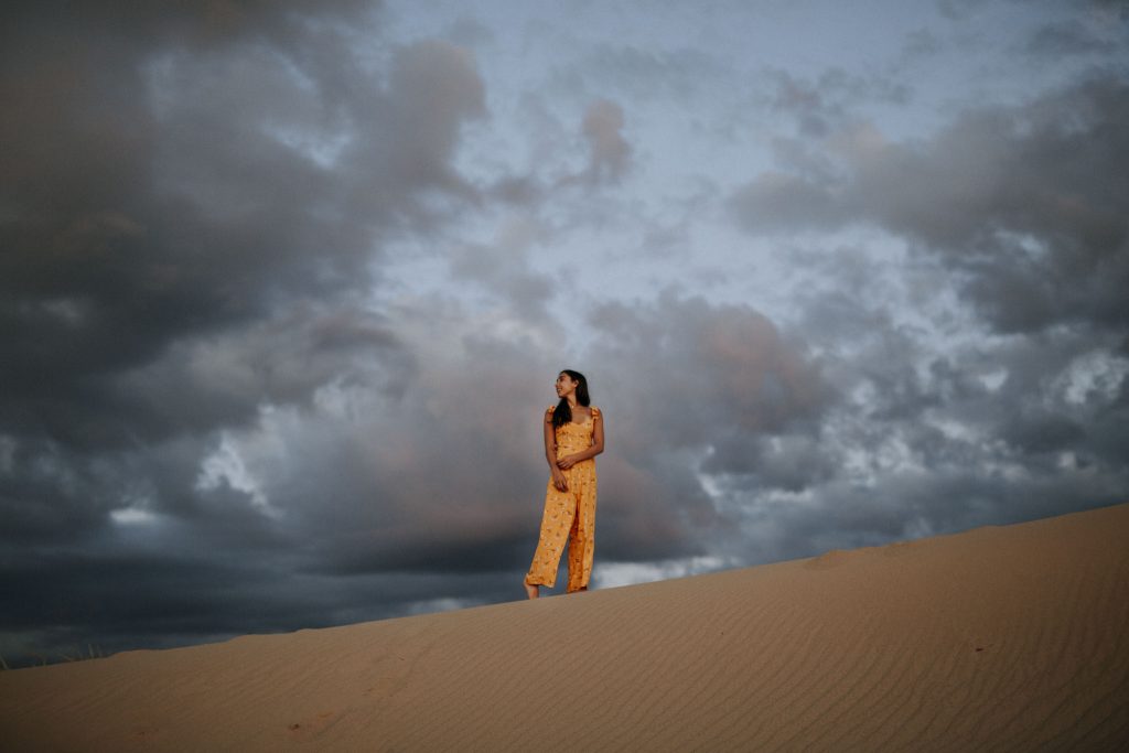 Standing at the top of the dunes in an orange jumpsuit