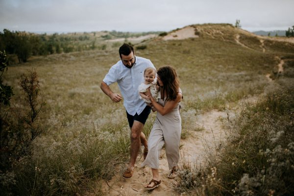 family running on the dunes with baby on pierce stocking scenic drive