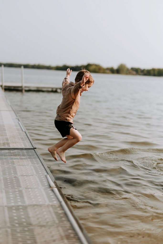 kid jumping off a dock at a traverse city beach