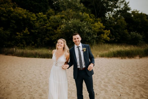 Bride and groom laughing on the beach of lake michigan