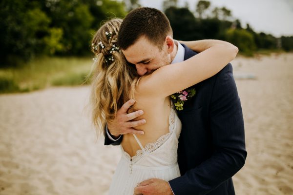 Bride and groom hugging on the beach of lake michigan