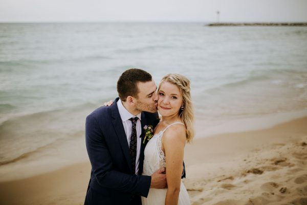 Bride and groom kissing on the beach of lake michigan