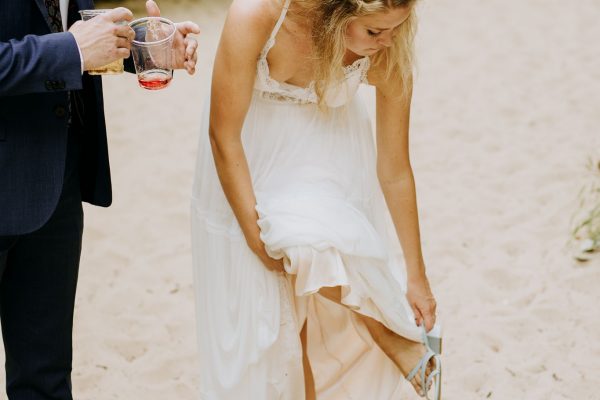 bride cleaning her shoes of sand on a beach of lake michigan